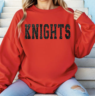 Red sweatshirt with 'KNIGHTS' text worn by a person sitting on steps.