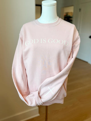 Pink sweatshirt with 'GOD IS GOOD' text on a mannequin against a neutral background
