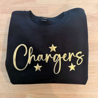 Folded black sweatshirt with 'Chargers' in gold letters on a wooden surface