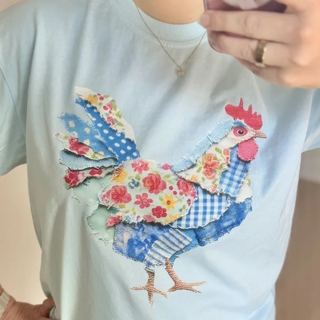 T-shirt with a colorful rooster design on a light blue background