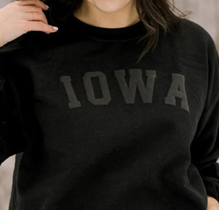 Person wearing a black 'Iowa' sweatshirt in a snowy outdoor setting