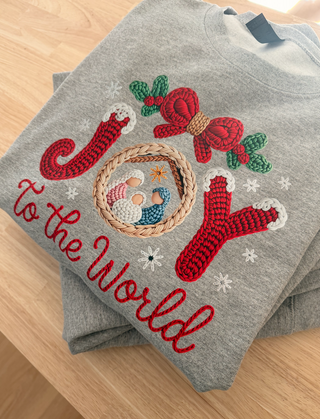Gray sweater with Christmas-themed embroidery on a wooden surface