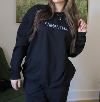 a girl wearing a black embroidered sweatshirt with a custom name similar to momtok